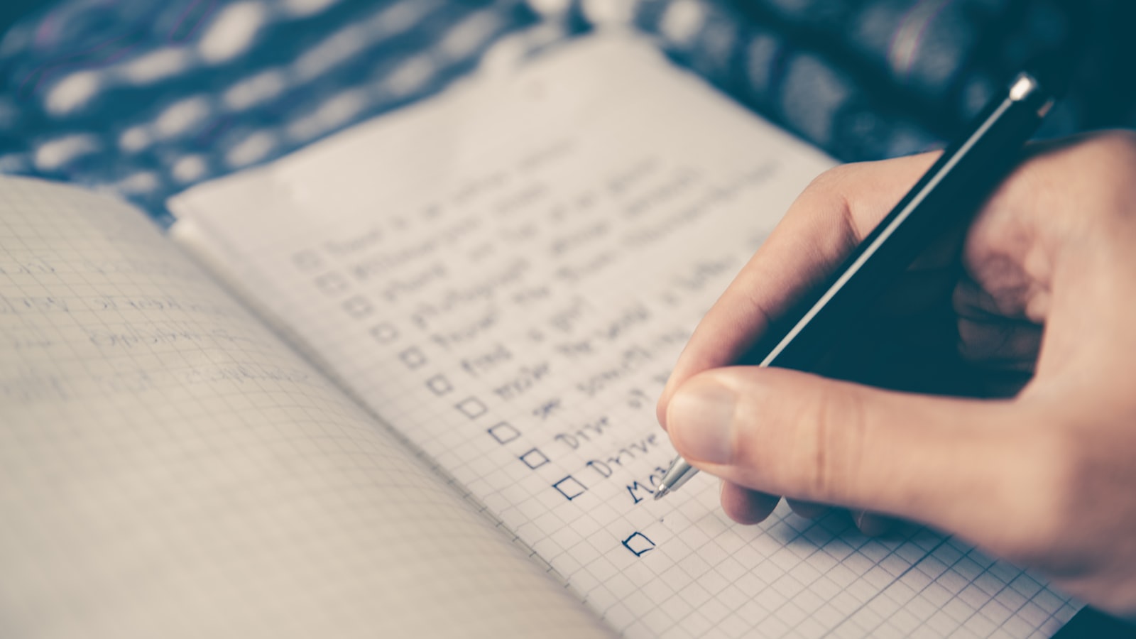 A weekly paper planner open on a desk with a few time slots marked in pencil.