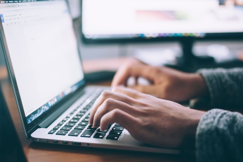 A laptop and a notebook on a clean desk in a quiet, sunlit room with no clutter.